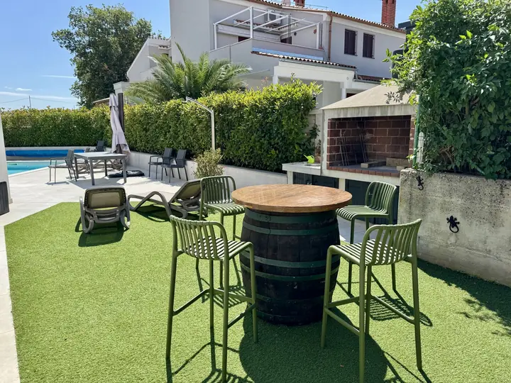 Lounge-Bereich im Garten neben Pool und Grill